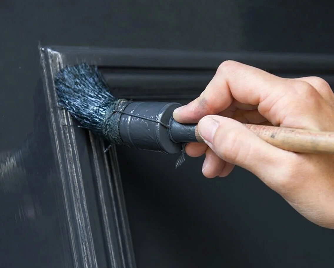 Schilder bezig met buitenschilderwerk aan een woning